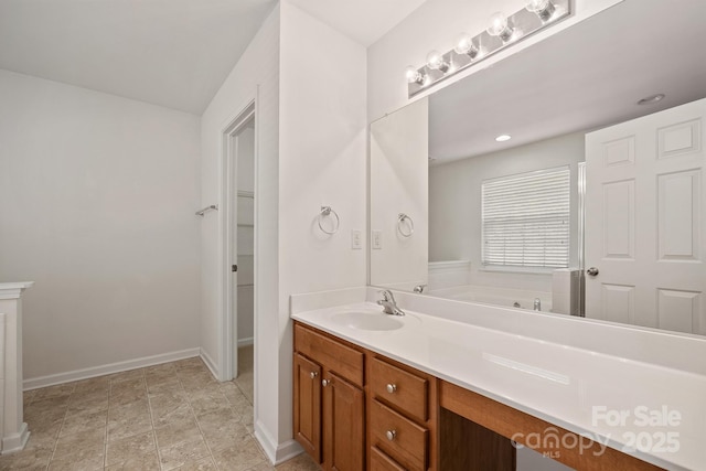 full bathroom with a spacious closet, vanity, and baseboards