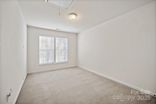 spare room with visible vents, carpet floors, attic access, and baseboards