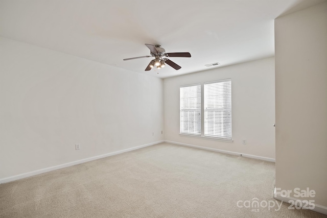 spare room with baseboards, a ceiling fan, visible vents, and light colored carpet