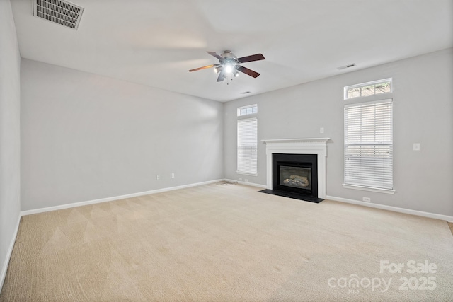 unfurnished living room featuring carpet, plenty of natural light, a fireplace with flush hearth, and visible vents