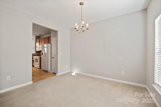 empty room with a notable chandelier, baseboards, and light colored carpet