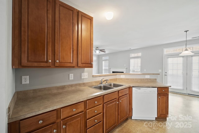 kitchen featuring brown cabinetry, white dishwasher, a peninsula, and a sink