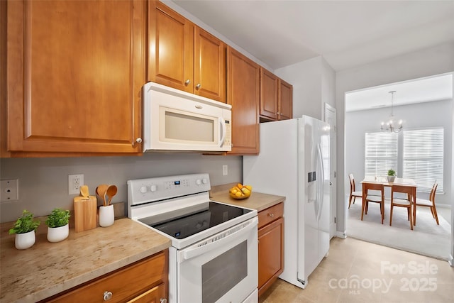 kitchen with light tile patterned floors, white appliances, brown cabinets, decorative light fixtures, and an inviting chandelier