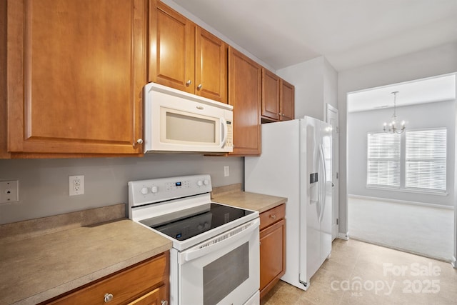 kitchen with a chandelier, white appliances, light countertops, brown cabinets, and decorative light fixtures