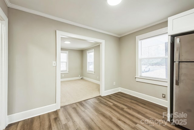 unfurnished room featuring light wood-style flooring, baseboards, and crown molding