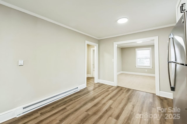 unfurnished room featuring ornamental molding, light wood finished floors, a baseboard radiator, and baseboards