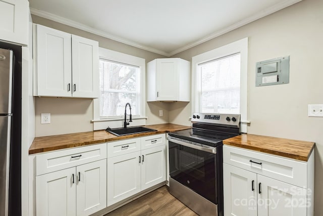 kitchen featuring appliances with stainless steel finishes, white cabinetry, a sink, and wood counters