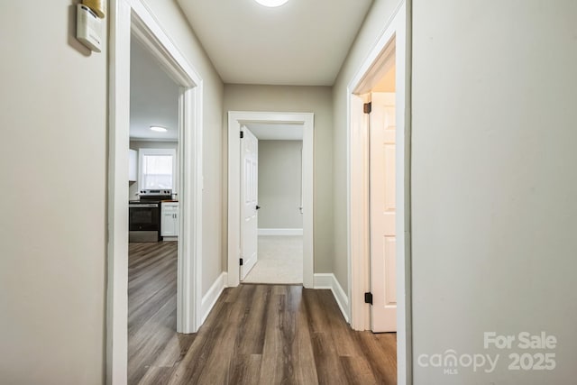 corridor featuring dark wood finished floors and baseboards