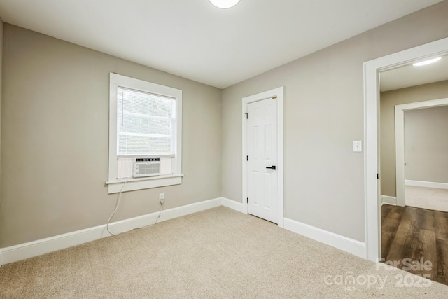 carpeted spare room with baseboards and cooling unit