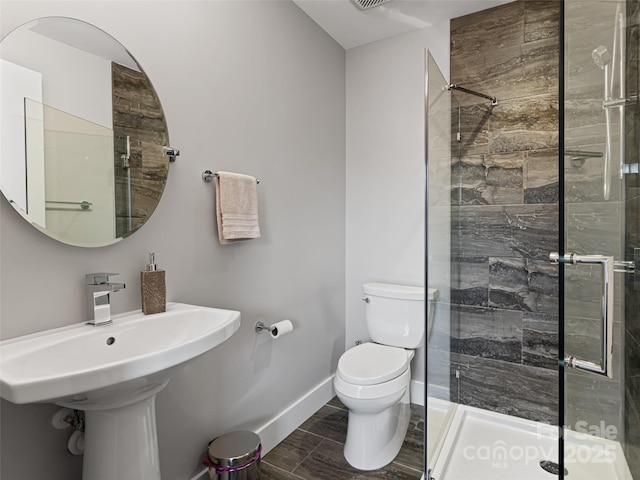 bathroom with wood finish floors, baseboards, a shower stall, and toilet