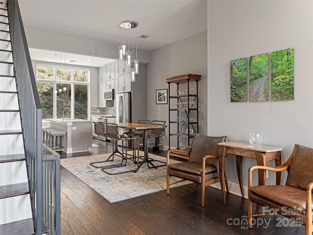 dining space with stairs, visible vents, and dark wood-style flooring