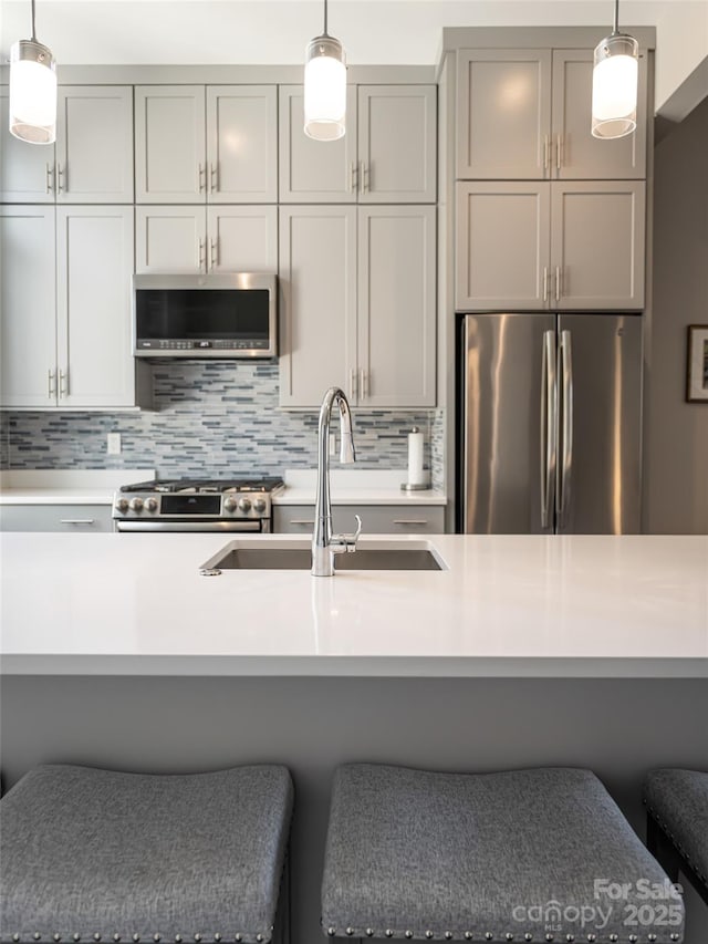 kitchen featuring stainless steel appliances, pendant lighting, and light countertops