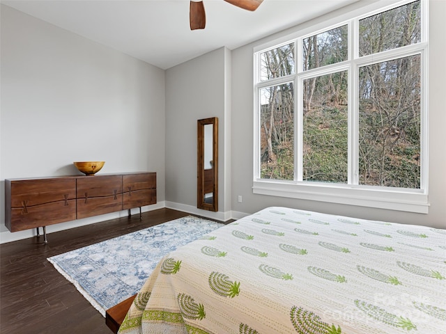 bedroom with dark wood-style flooring, multiple windows, a ceiling fan, and baseboards