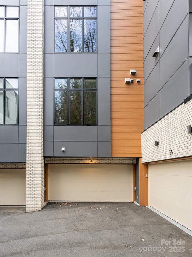 exterior space featuring a garage, brick siding, driveway, and stucco siding