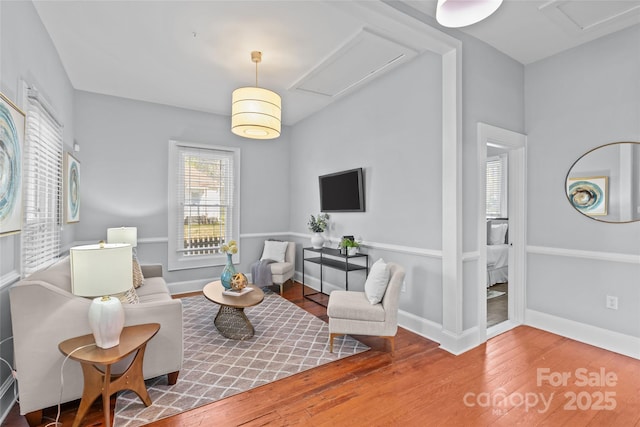 living area featuring wood finished floors, attic access, and baseboards