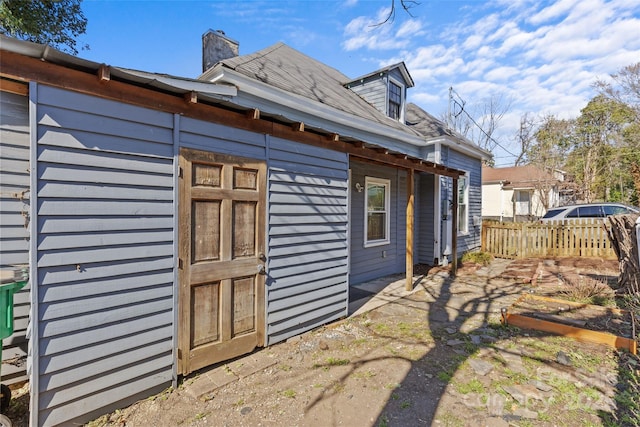 view of property exterior featuring a chimney and fence