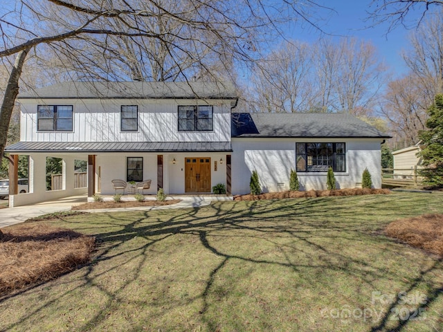 modern inspired farmhouse with brick siding, a porch, a front yard, a standing seam roof, and metal roof