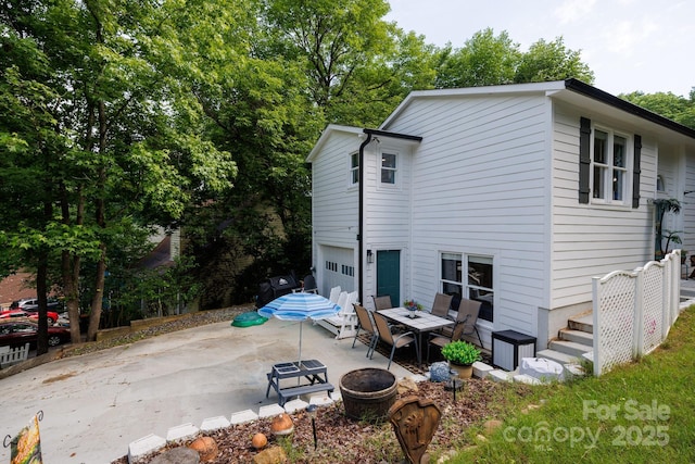 back of property with a fire pit, concrete driveway, a patio, and an attached garage