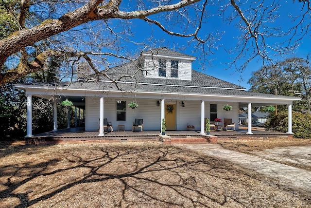 farmhouse-style home with a porch and a shingled roof