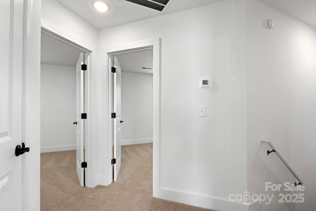 corridor featuring light carpet, visible vents, and baseboards