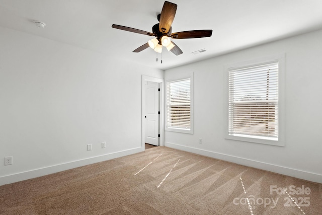 unfurnished room featuring baseboards, visible vents, ceiling fan, and light colored carpet