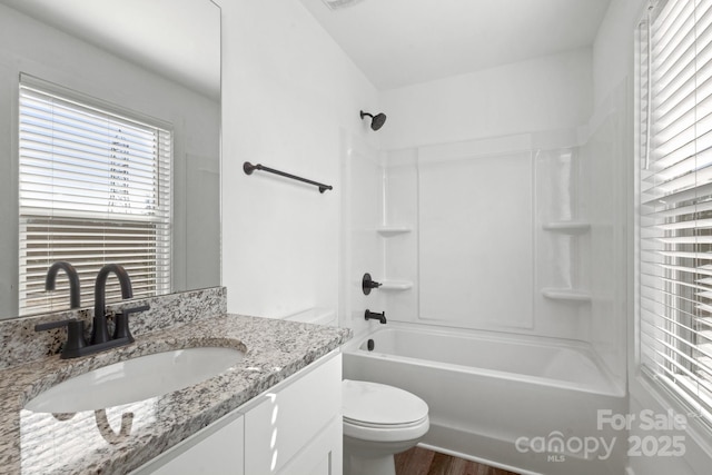 bathroom featuring toilet, wood finished floors, visible vents, vanity, and washtub / shower combination