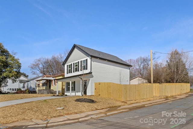 view of side of home with a porch and fence