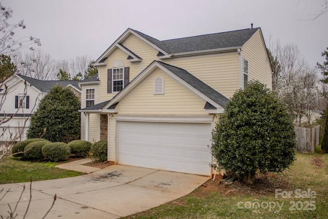 traditional-style house featuring a garage, a shingled roof, fence, and concrete driveway