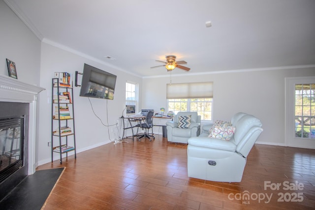 living room featuring a wealth of natural light, a fireplace with flush hearth, crown molding, and wood finished floors