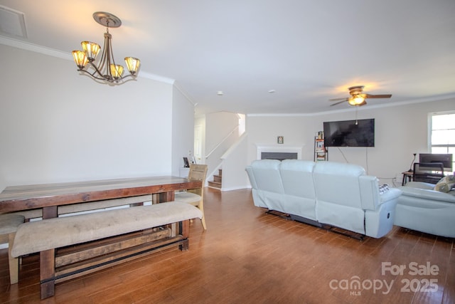 living room featuring ornamental molding, visible vents, a fireplace, and wood finished floors