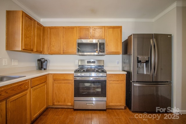 kitchen with dark wood-style floors, stainless steel appliances, light countertops, ornamental molding, and a sink