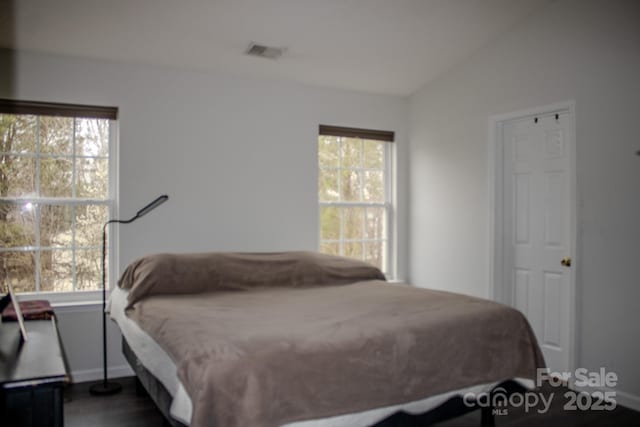 bedroom with lofted ceiling, multiple windows, visible vents, and baseboards