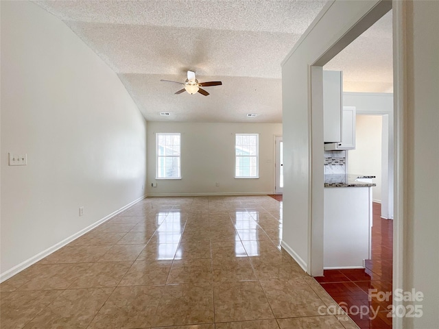 tiled empty room with visible vents, a ceiling fan, baseboards, and a textured ceiling