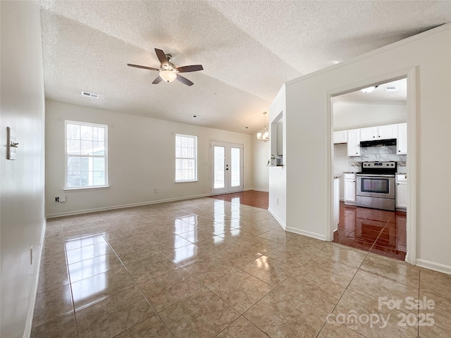 unfurnished living room with vaulted ceiling, baseboards, visible vents, and ceiling fan