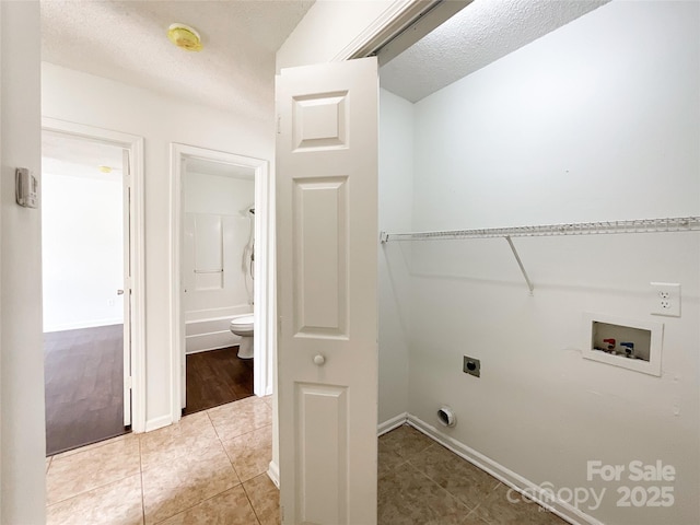 clothes washing area with hookup for a washing machine, light tile patterned floors, baseboards, hookup for an electric dryer, and laundry area