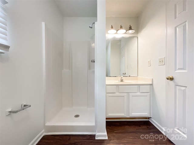 bathroom with vanity, a shower stall, wood finished floors, and baseboards