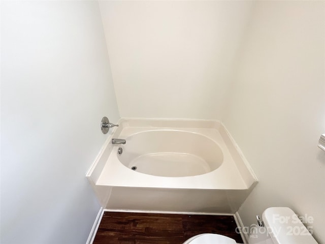 bathroom featuring a garden tub and toilet