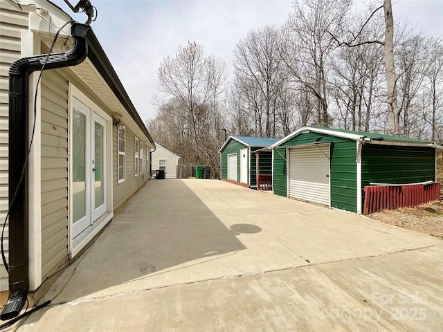 exterior space with french doors, a detached garage, and an outbuilding