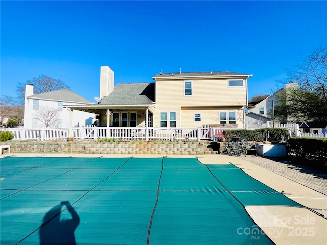 back of property with a patio, a chimney, fence, and a fenced in pool