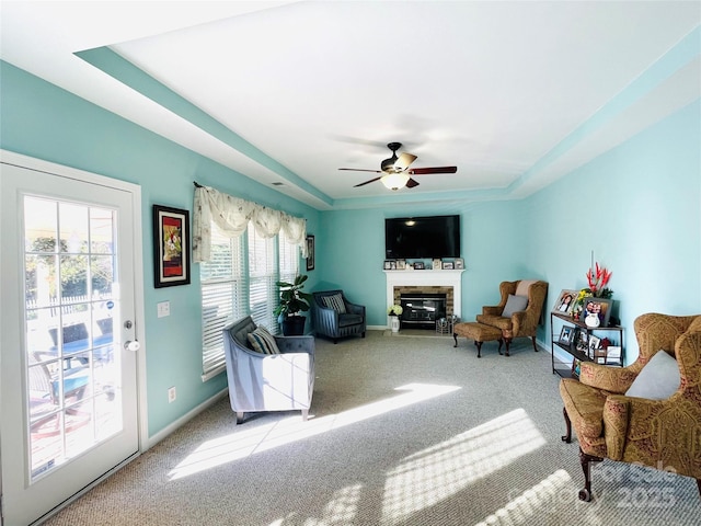 living room featuring carpet floors, a glass covered fireplace, a ceiling fan, and baseboards