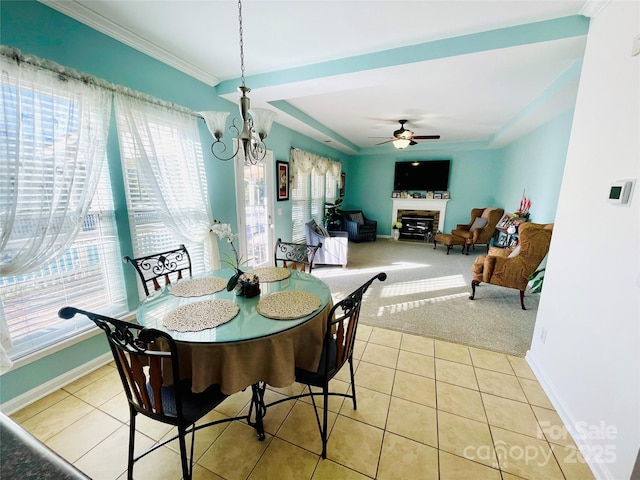 dining room with light tile patterned floors, light colored carpet, a glass covered fireplace, crown molding, and ceiling fan with notable chandelier