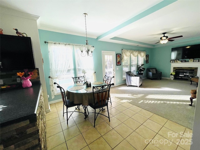 dining area with light tile patterned floors, light colored carpet, ceiling fan with notable chandelier, baseboards, and a glass covered fireplace