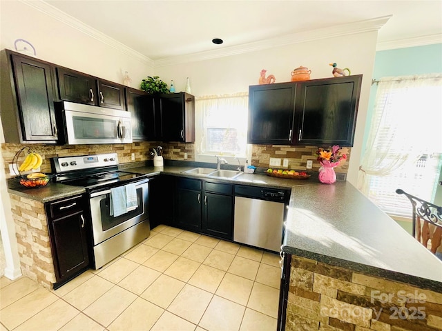 kitchen with dark countertops, a sink, stainless steel appliances, crown molding, and backsplash