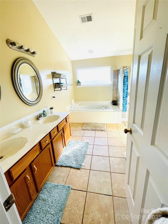 bathroom with visible vents, tile patterned floors, a sink, a textured ceiling, and a bath