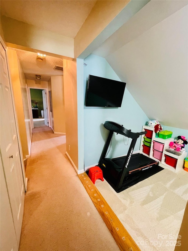 workout area with vaulted ceiling, carpet, visible vents, and baseboards