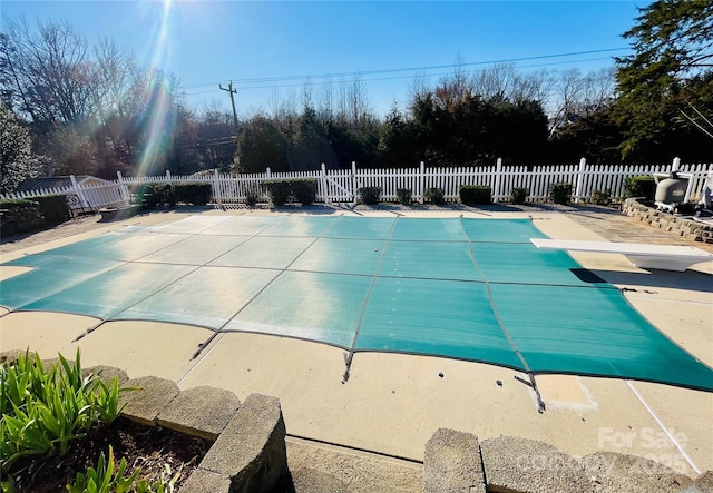 view of swimming pool with fence, a diving board, a fenced in pool, and a patio