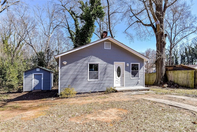 bungalow featuring a storage shed, a chimney, an outbuilding, and fence