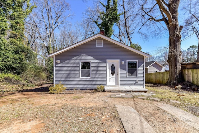 bungalow-style house featuring fence and a chimney