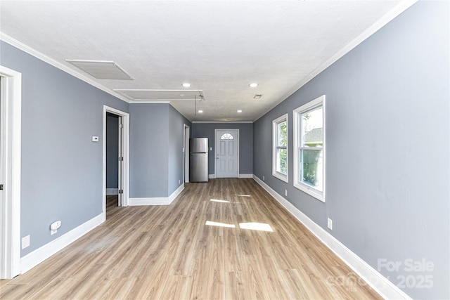 interior space with visible vents, baseboards, light wood finished floors, attic access, and crown molding