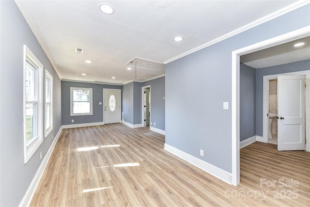 interior space featuring attic access, visible vents, baseboards, crown molding, and light wood-type flooring